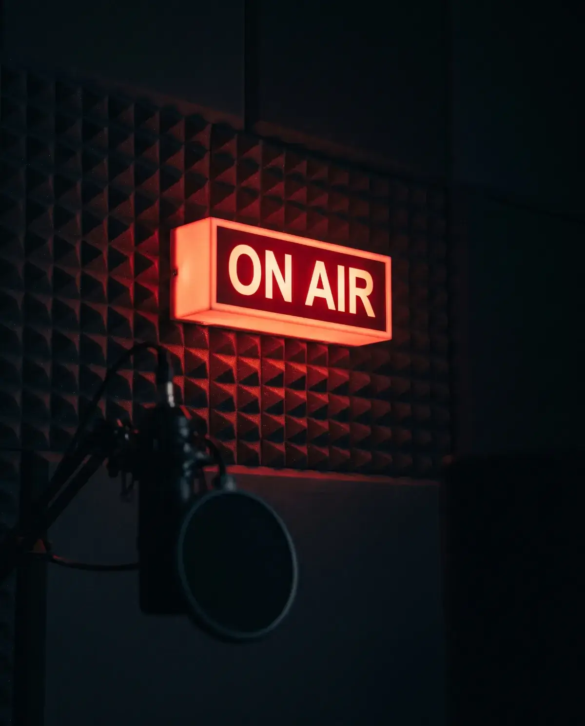 A lit red ON AIR sign in the Booked Out podcast studio